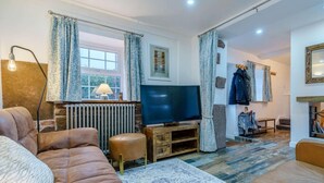 Un salon avec un canapé, un téléviseur, un radiateur et une fenêtre avec des rideaux.
