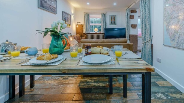 Un coin repas avec une table mise pour le petit-déjeuner, un canapé, un téléviseur et une carte accrochée au mur.