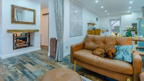 Un salon avec un canapé en cuir marron, une table basse en bois et un chien qui se repose sur le canapé.