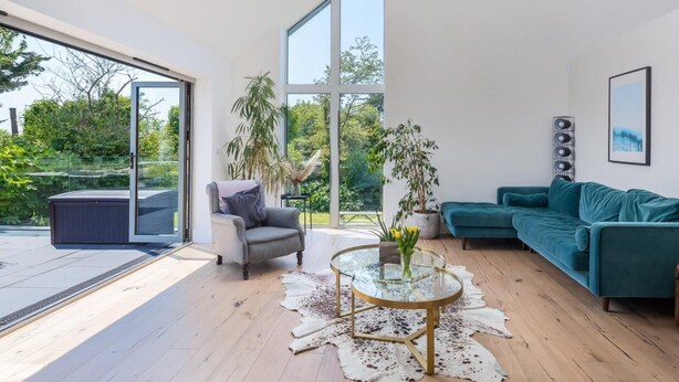 Uma sala de estar moderna com uma mesa de centro de vidro, um sofá verde-água e uma poltrona cinza.