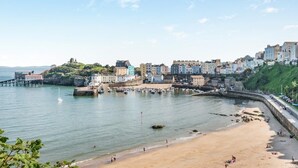 A coastal town with buildings along the waterfront, a sandy beach, and a pier extending into the water. - 2 Bed in Clynderwen (oc-86158) (Clynderwen)