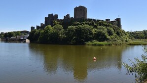 Eine historische Burg auf einem Hügel mit Blick auf einen ruhigen Fluss.
