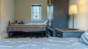Ein Schlafzimmer mit Bett, Fenster mit Blick, Nachttisch mit Lampe und Kleiderschrank.