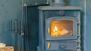 Ein Kaminofen mit Feuer, einem Metalleinsatz und einer Steinwand.