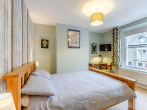 A bedroom with a bed, bedside table, lamp, and a window with a view of a house. - 3 Bed in Keswick (oc-86162) (Keswick)