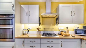 Een keuken met witte kastjes, een fornuis, een magnetron en een broodrooster.