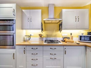 A kitchen with white cabinets, a stove, a microwave, and a toaster. - 3 Bed in Keswick (oc-86162) (Keswick)
