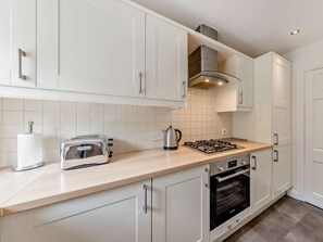A modern kitchen with white cabinets, a gas stove, a toaster, and a kettle. - 3 Bed in Aberdyfi (oc-dy007) (Aberdovey)