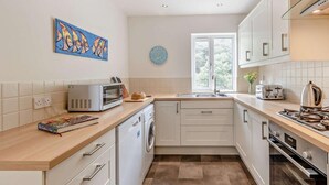 A modern kitchen with a microwave, toaster, sink, and oven. - 3 Bed in Aberdyfi (oc-dy007) (Aberdovey)