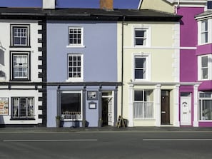 A row of colorful townhouses with distinct architectural styles, including a shop with a visible window display and signage.
