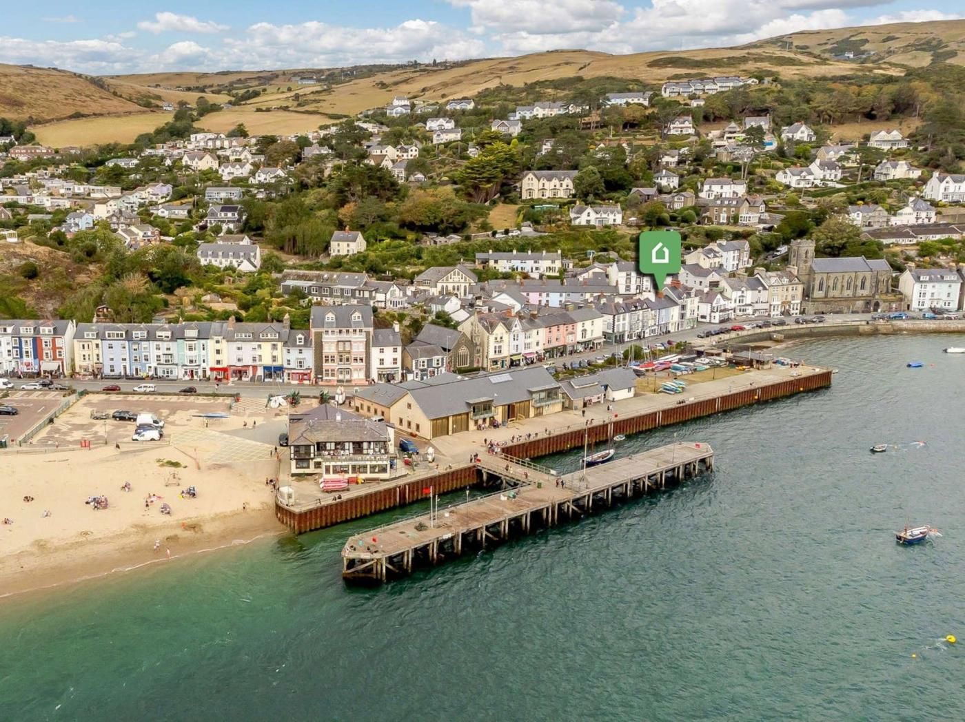 Une ville côtière dotée d’une jetée qui s’avance dans la mer, entourée d’immeubles d’habitation et d’une église.