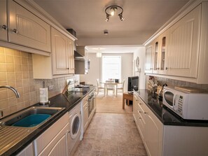Une cuisine équipée d’un lave-linge, d’un four à micro-ondes et d’un coin repas avec une table et des chaises.