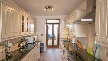 A kitchen with white cabinets, a built-in oven, a microwave, and a sink.