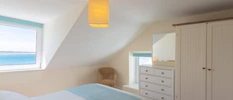 A bedroom with a bed, a dresser, a chair, a window with a view, and a ceiling light.