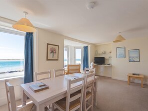 Ein Zimmer mit Esstisch, Stühlen, einem Fernseher und Kunstwerken an den Wänden.