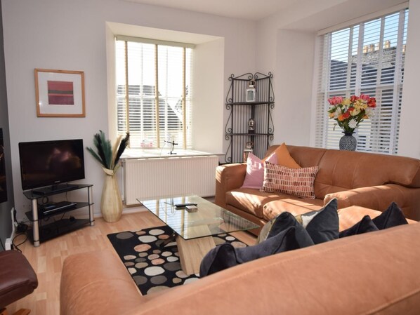 Een woonkamer met een bank, salontafel en een televisie op een dressoir.