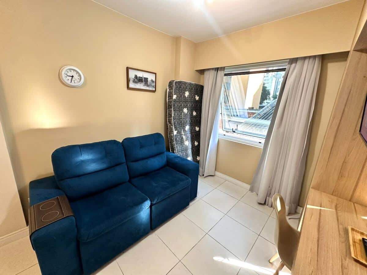 A living room with a blue sofa, a clock on the wall, and a window with curtains.