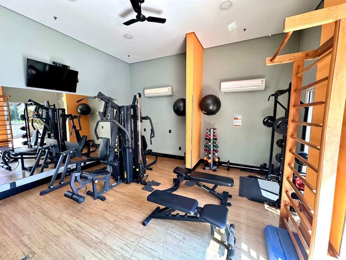 Un gimnasio con equipo de ejercicio, un televisor y una estructura de madera.