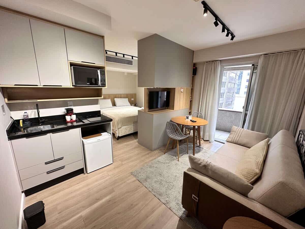 Une chambre d’hôtel compacte comprenant un coin cuisine, un lit, un espace salon et un téléviseur.