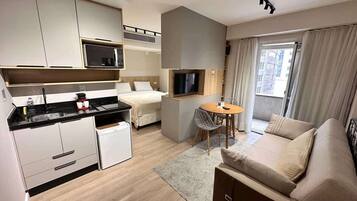 Une chambre d’hôtel compacte comprenant un coin cuisine, un lit, un espace salon et un téléviseur.