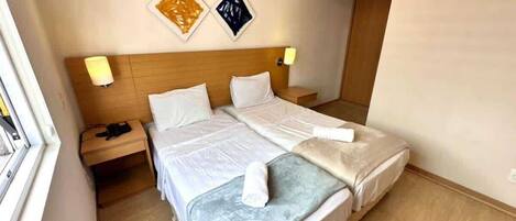 A hotel room with a bed, bedside tables, and wall art.
