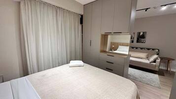 A modern bedroom with a bed, a bedside table, a wardrobe, and a mirror.