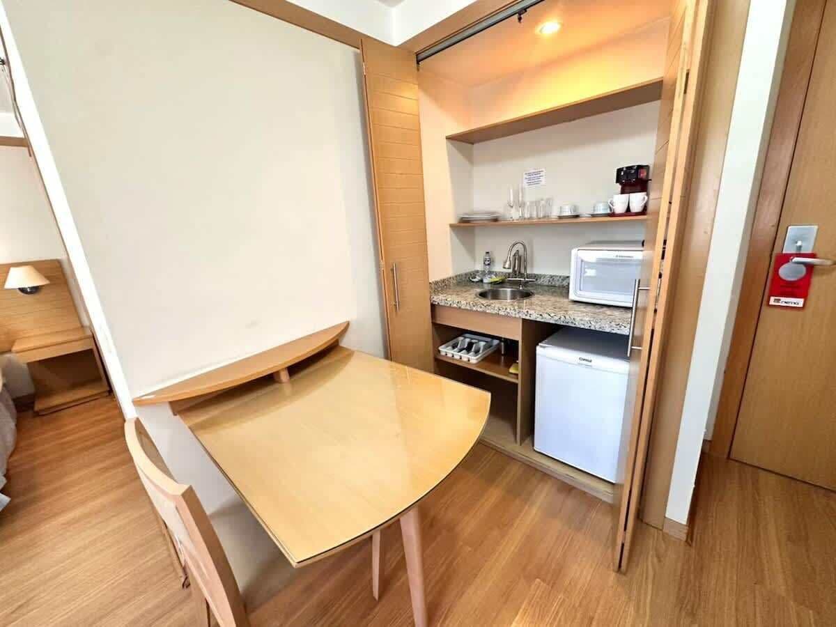Una kitchenette compacta con microondas, cafetera y un refrigerador pequeño.