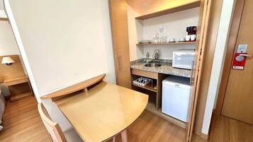 Una kitchenette compacta con microondas, cafetera y un refrigerador pequeño.