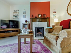Ein Wohnzimmer mit Kamin, Fernseher, Couchtisch und Sofa.