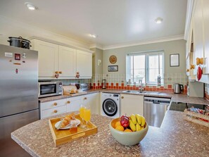 Eine Küche mit Kühlschrank, Mikrowelle, Backofen und Waschmaschine.
