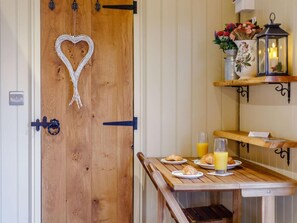 Een houten deur met hartvormige decoratie, een ontbijttafel met croissants en sinaasappelsap, en een plank met bloemen en een lantaarn.