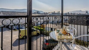 Ein Balkon mit Blick auf einen Parkplatz, ein Tisch mit einer Serviertablett und ein Metallgeländer.