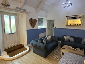 Ein Wohnzimmer mit einem blauen Sofagarnitur, einer Holztür und einer Kronleuchter.