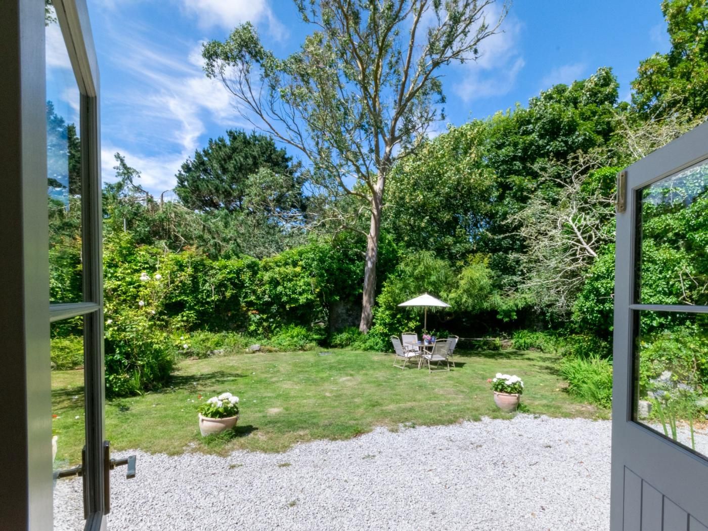 A garden with a patio table and chairs, surrounded by lush greenery and trees.