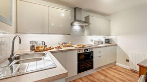 Een moderne keuken met een dubbele spoelbak, een magnetron, een oven en houten vloeren.