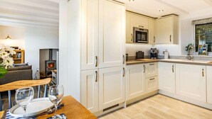 Uma cozinha moderna com armários brancos, forno embutido e sala de jantar com mesa e cadeiras de madeira.