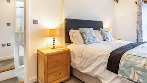 Um quarto com cama, mesas de cabeceira e cabeceira de madeira.