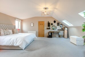 A bedroom with a bed, a desk, a chair, a radiator, a wooden door, a mirror, and a skylight. - 3 Bed in Barnstaple (oc-87116) (Fremington)