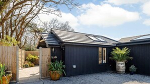 A black building with a sloped roof, a wooden fence, and gravel ground. - 1 Bed in Wareham (oc-87150) (Ridge)