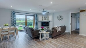 Un salon moderne comprenant un canapé, un téléviseur et un coin repas avec des chaises et une table.