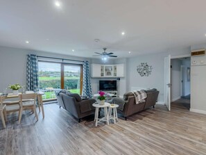 Ein modernes Wohnzimmer mit einer Couch, einem Fernseher und einem Essbereich mit Stühlen und einem Tisch.
