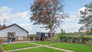 Une propriété résidentielle comprenant une maison blanche, une cour clôturée et un grand arbre.