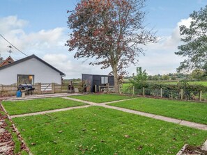 Ein Wohnhaus mit weißer Fassade, einem eingezäunten Garten und einem großen Baum.