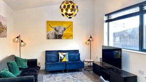 A modern living room with a blue sofa, a television, and a large window.