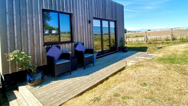 Un edificio moderno con rivestimento in legno, ampie finestre e una terrazza con posti a sedere all'aperto.