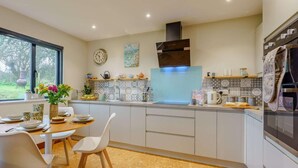 Una cucina moderna con mobili bianchi, un'ampia finestra e un'area pranzo con tavolo e sedie.