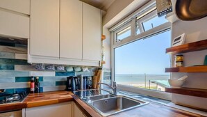 A modern kitchen with a large window, wooden countertop, and white cabinets. - 4 Bed in Bridgend (oc-87141) (Ogmore-by-Sea)