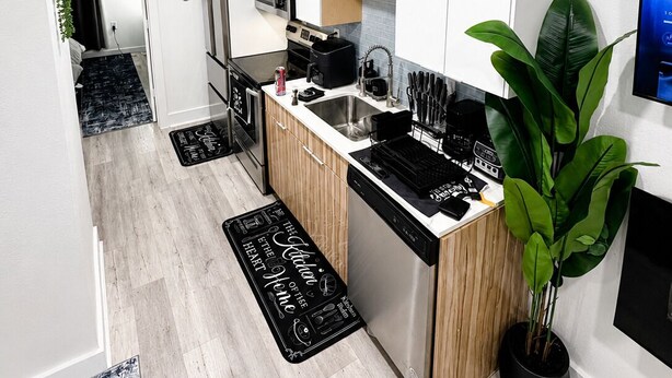 A modern kitchen with white cabinets, stainless steel appliances, and a black countertop. - Modern Luxe Escape with Spa Shower, Digital Fireplace & Prime Location (Dallas)