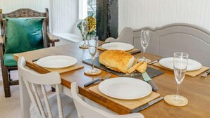 A dining table set with white plates, cutlery, and glasses, with a loaf of bread and a knife on the table. - 2 Bed in Ambleside (oc-87180) (Ambleside)