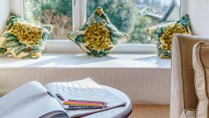 A room with a window sill, a chair, and a table with a sketchbook and colored pencils. - 2 Bed in Ambleside (oc-87180) (Ambleside)
